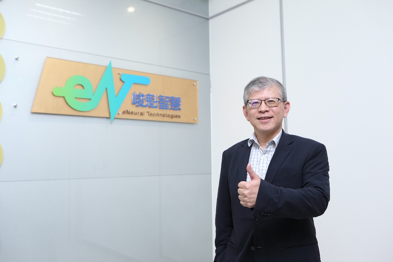 一個身著西裝的學者跟峻魁智慧招牌的合照